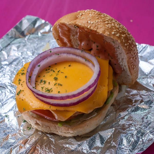 Vegan On The Fly burger with vegan cheese, red onion, and sauce on foil.