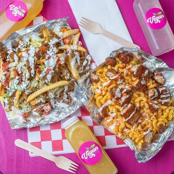 Vegan On The Fly's loaded fries and mac and cheese with vegan chicken, drinks, and wooden forks.