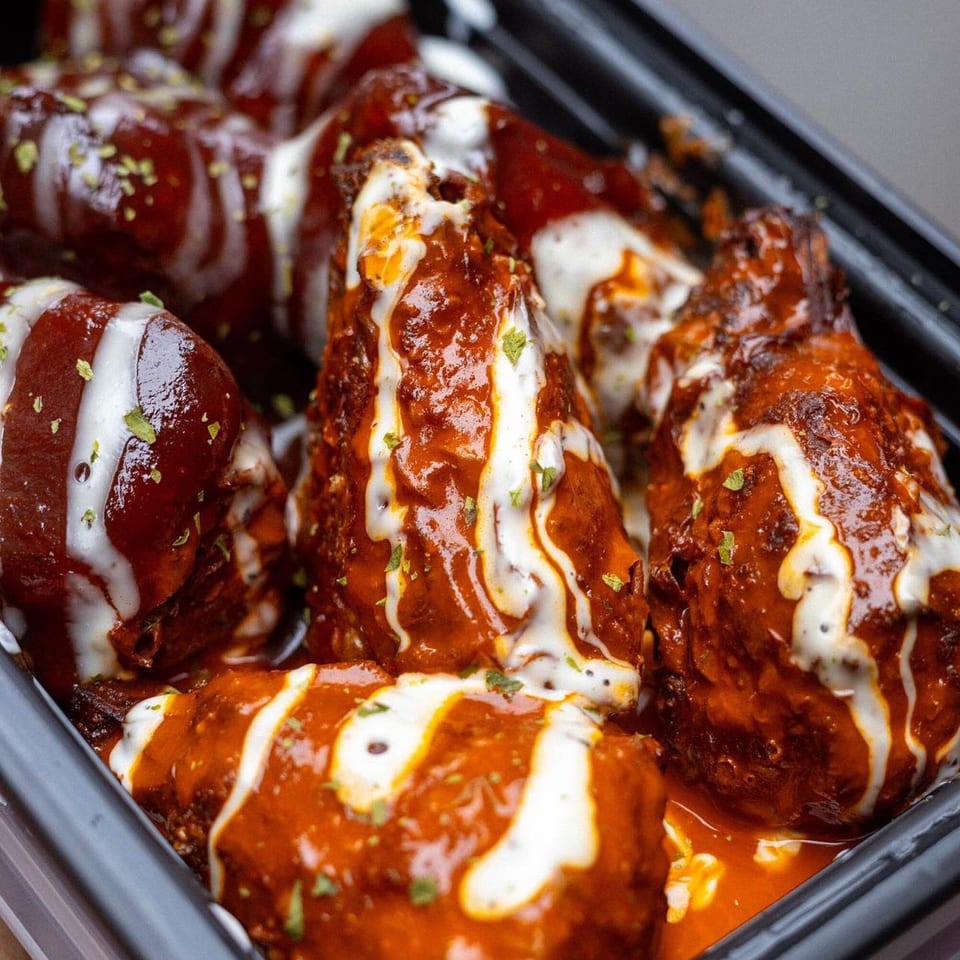 Close-up of Vegan On The Fly's vegan wings, drenched in red sauce, drizzled with white dressing.